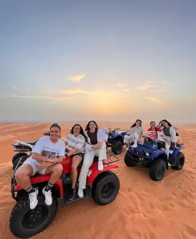 Group of friends on quad bikes at sunset in the Merzouga dunes